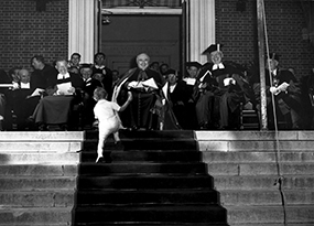 A toddler interrupts the Commencement ceremony by climbing up the chapel steps.